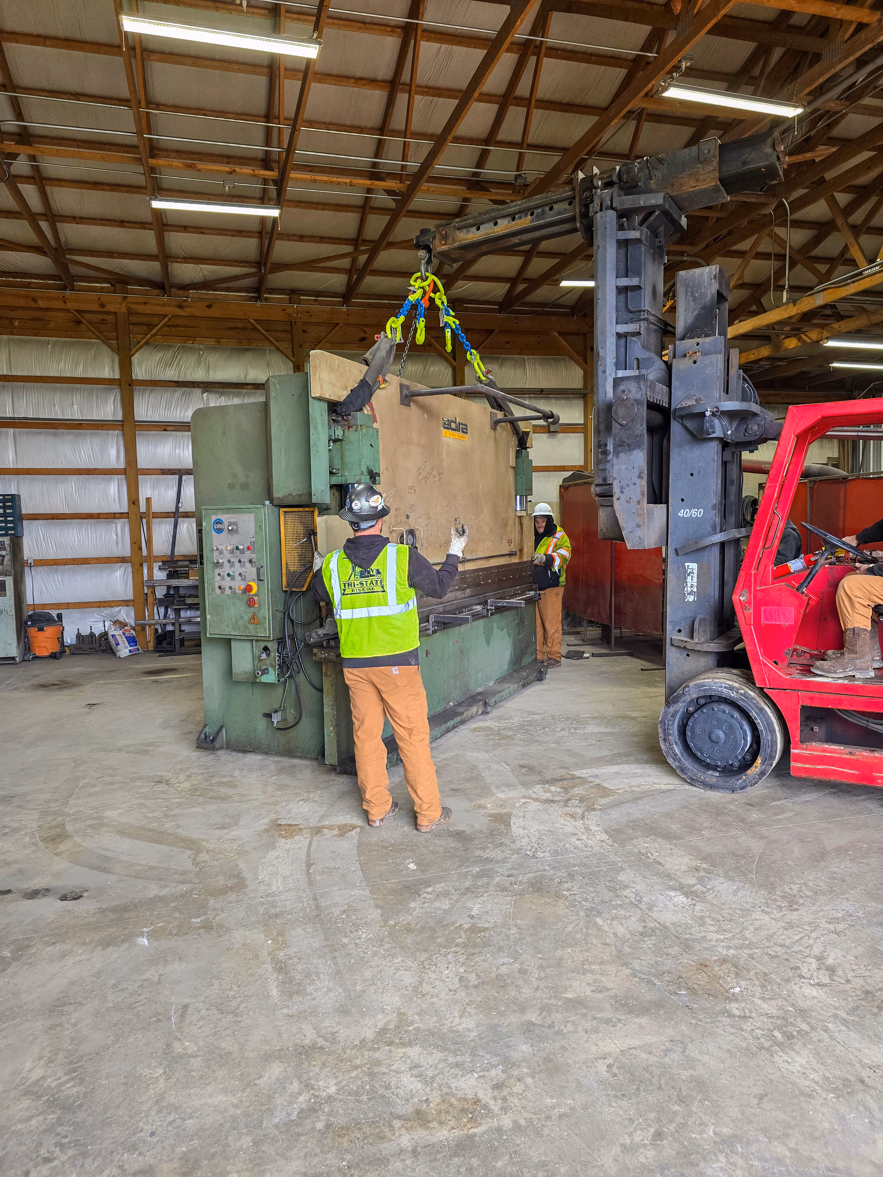 A TSR employee signaling a VersaLift operator while they move machinery