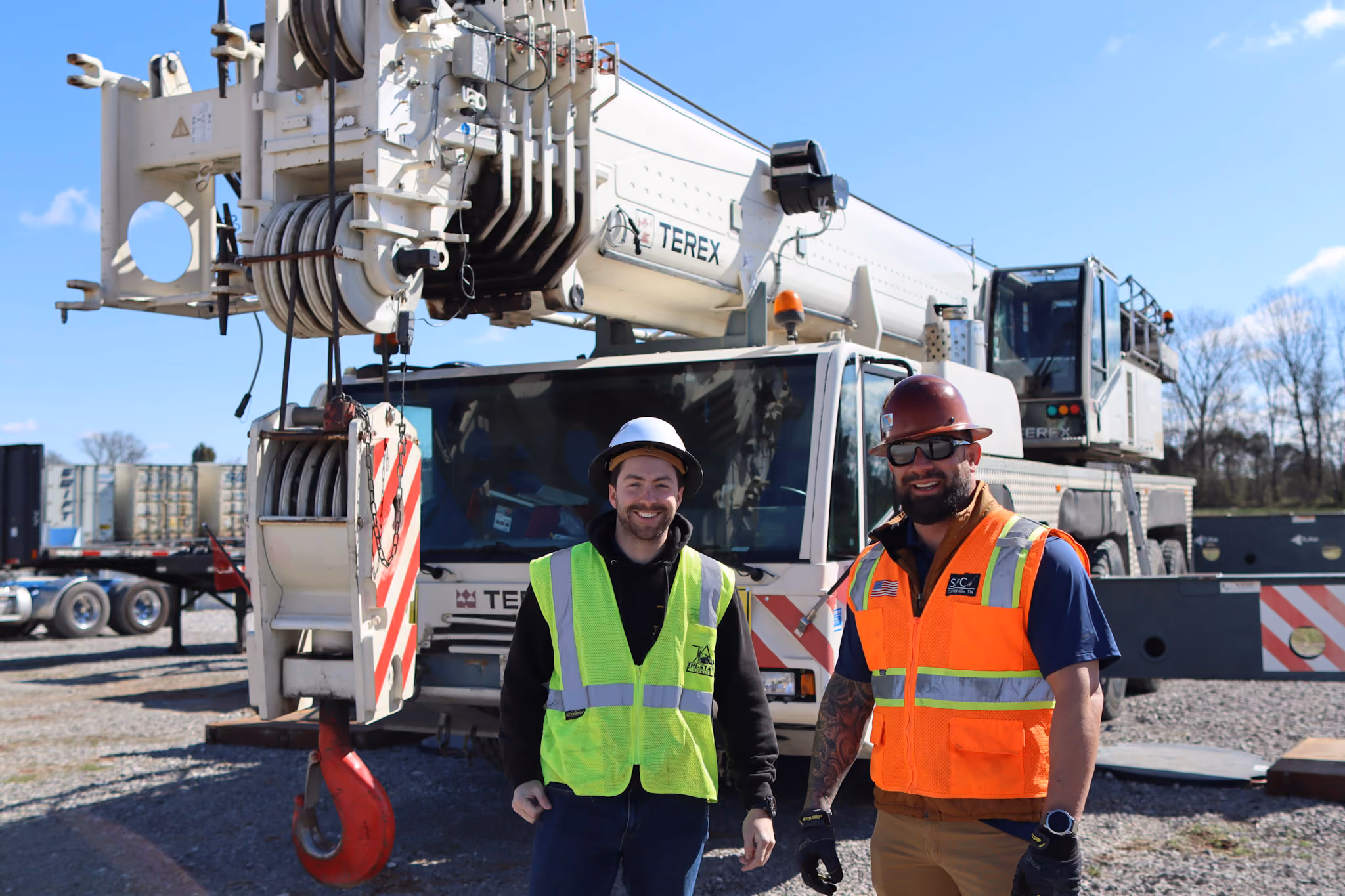 Two TSR employees standing in front of a boom truck crane
