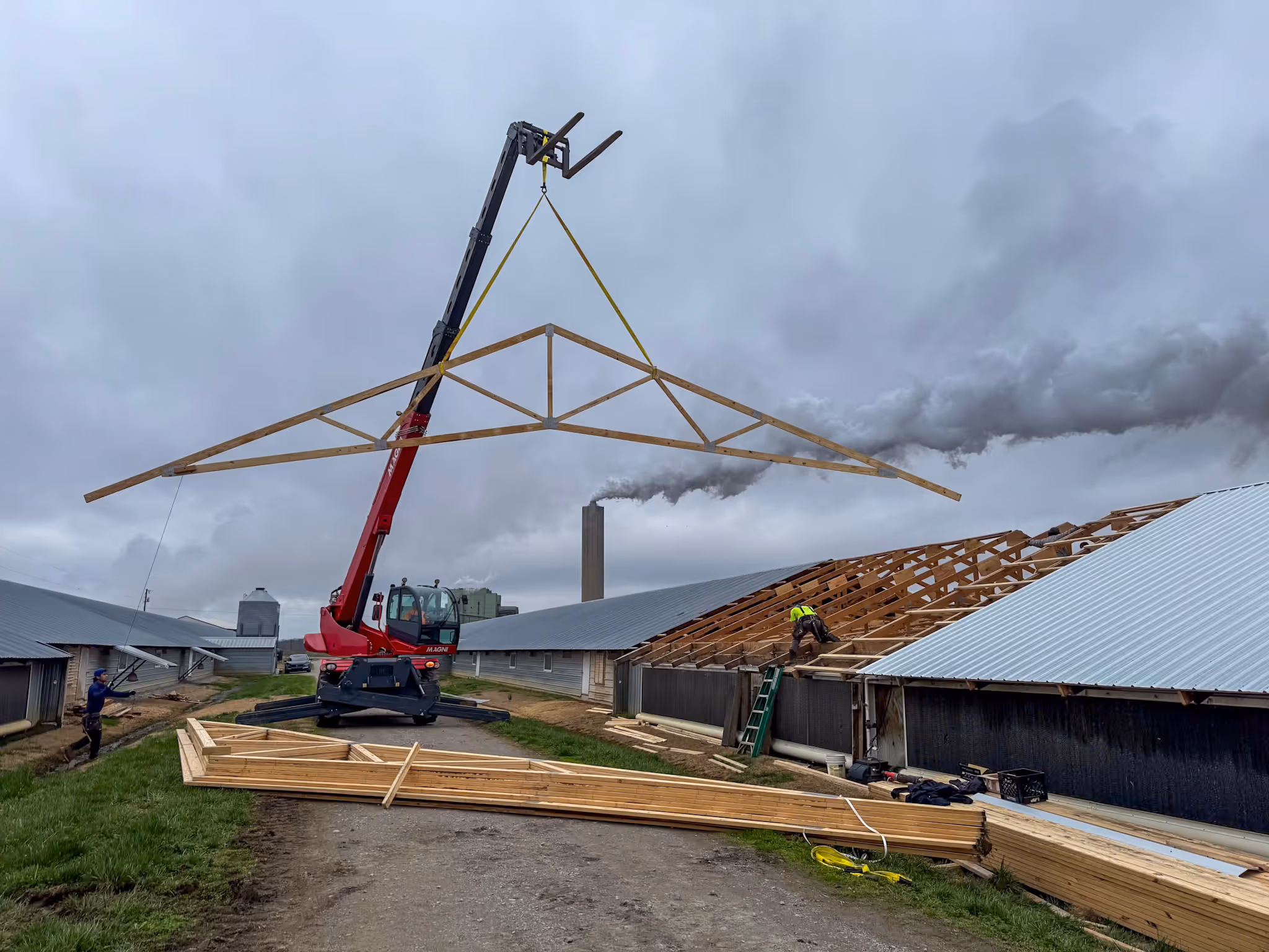 Trusses being lifted during a barn construction project