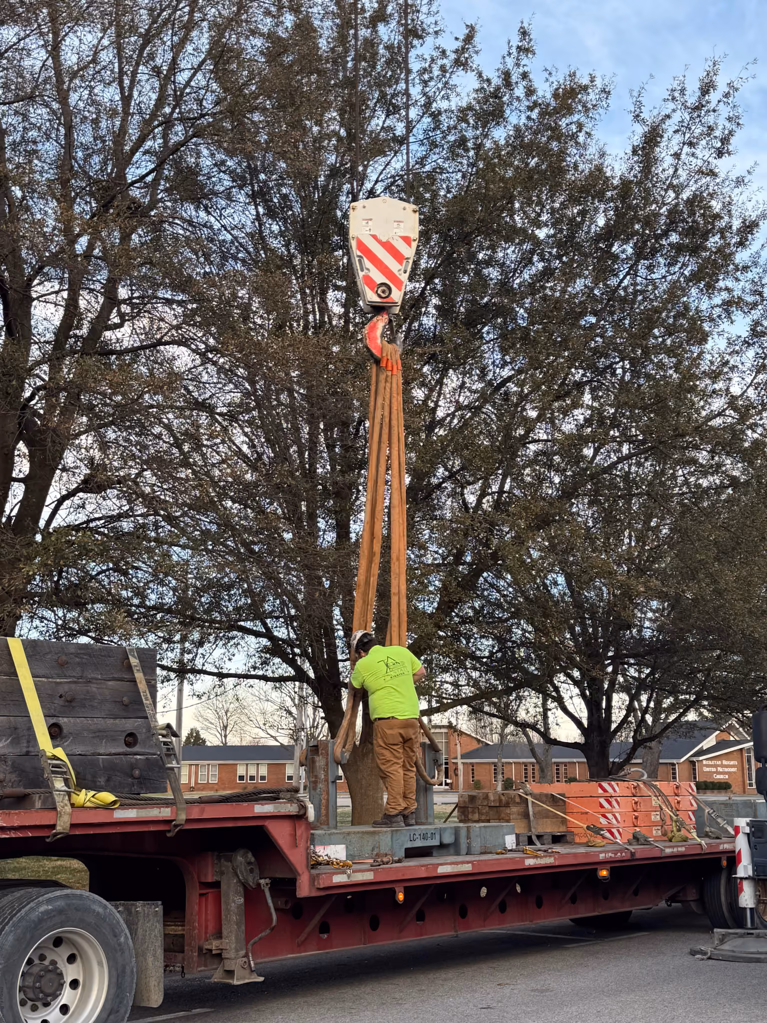 A TSR rigger standing on a flatbed while adjusting a crane's chain slings