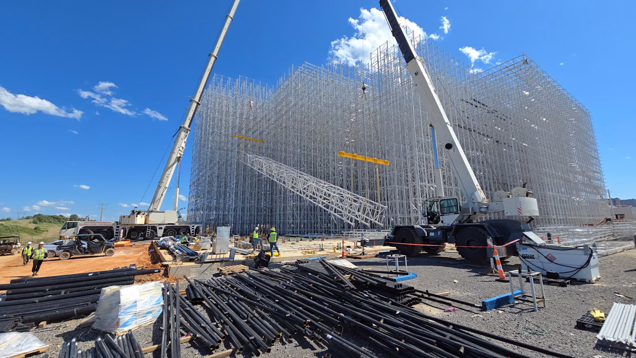Two cranes tandem lifting steel during a facility expansion