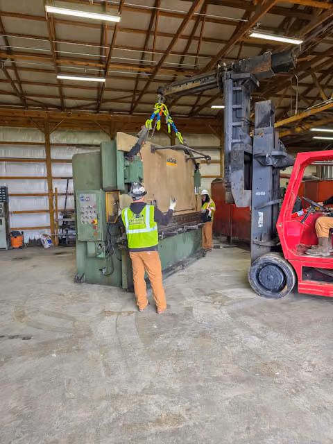 A VersaLift moving machinery while a TSR employee signals