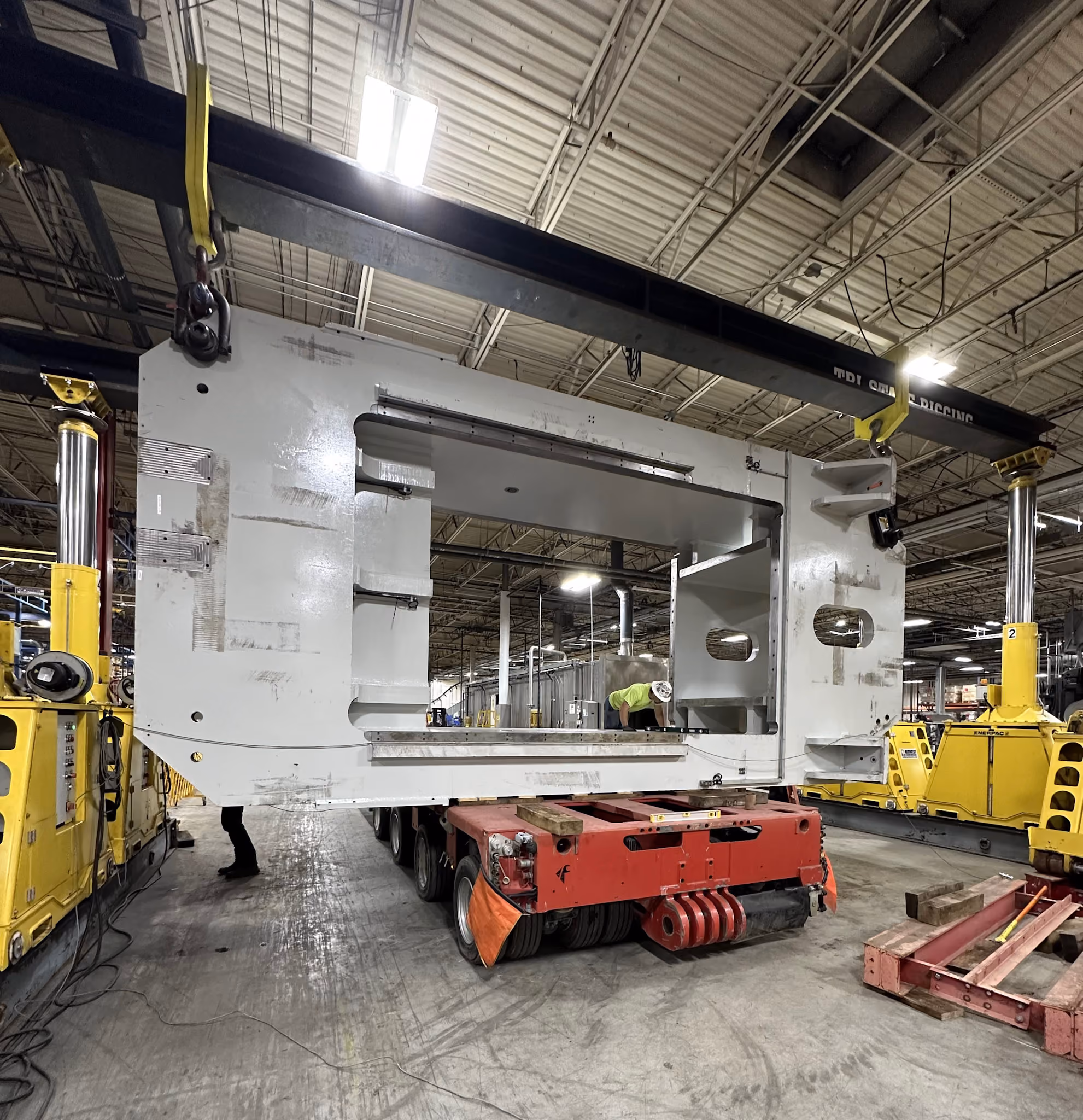 A gantry crane lifting a metal frame within a plant