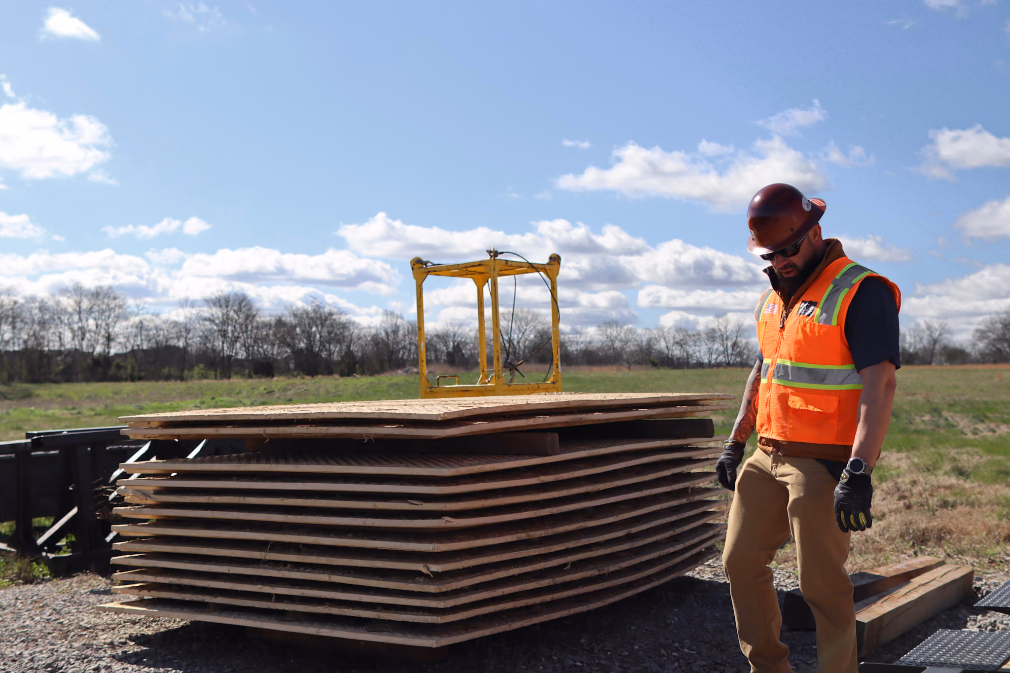 A TSR employee posed in front of a stack of ground protection mats