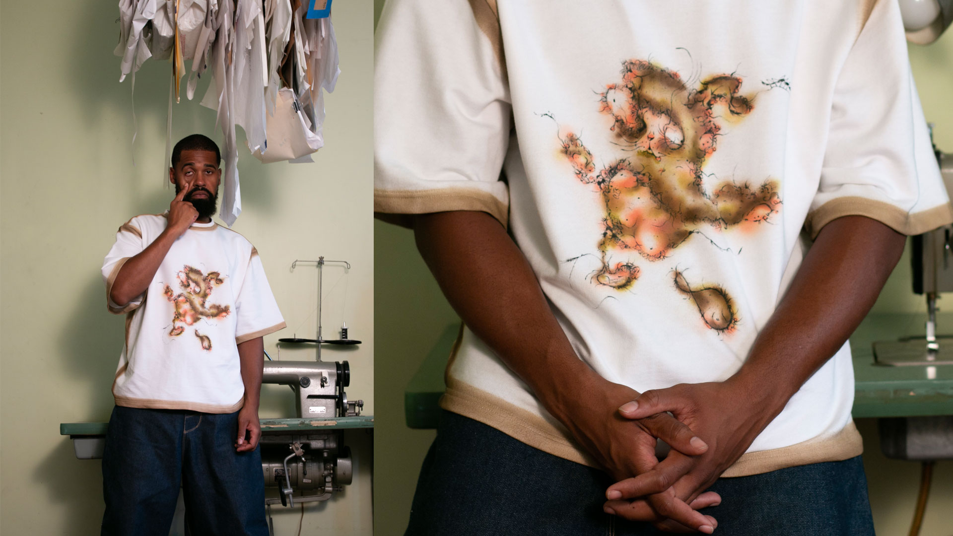 Man wearing a beige and white T-shirt with an abstract, colorful design, standing in front of a sewing machine.