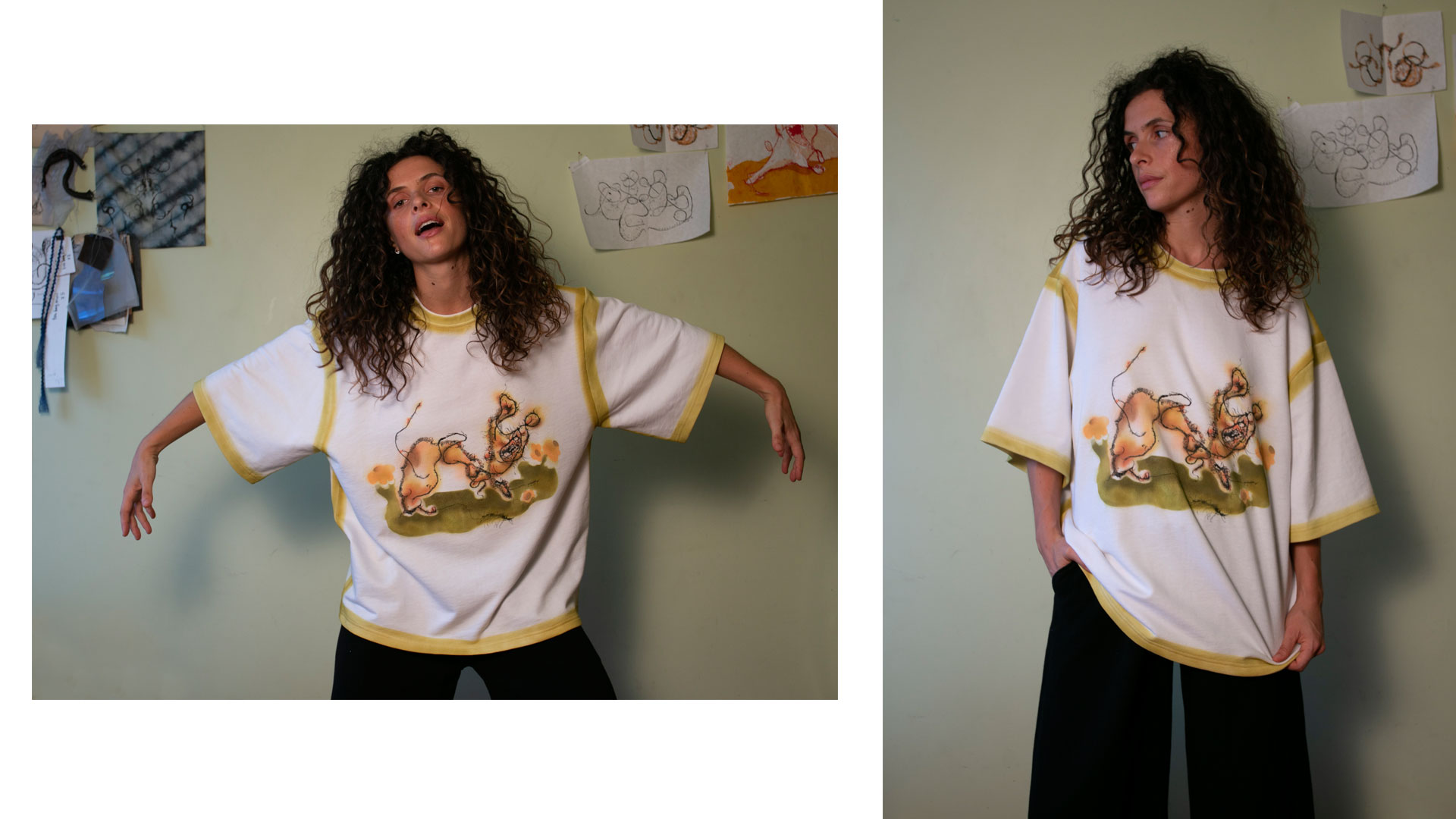 Woman with curly hair wearing a white oversized t-shirt with yellow trim and an abstract orange and green design, posing against a light green wall with sketches pinned to it.