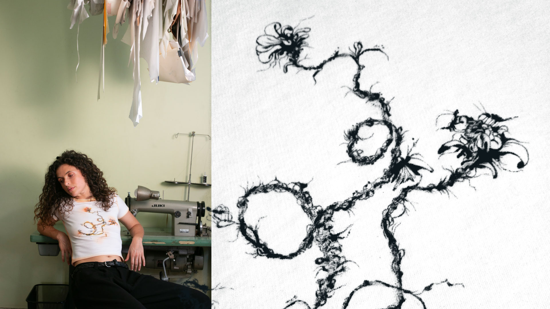 Woman with curly hair wearing a white T-shirt with a black pyrography floral design, sitting in front of a sewing machine with fabric hanging above.