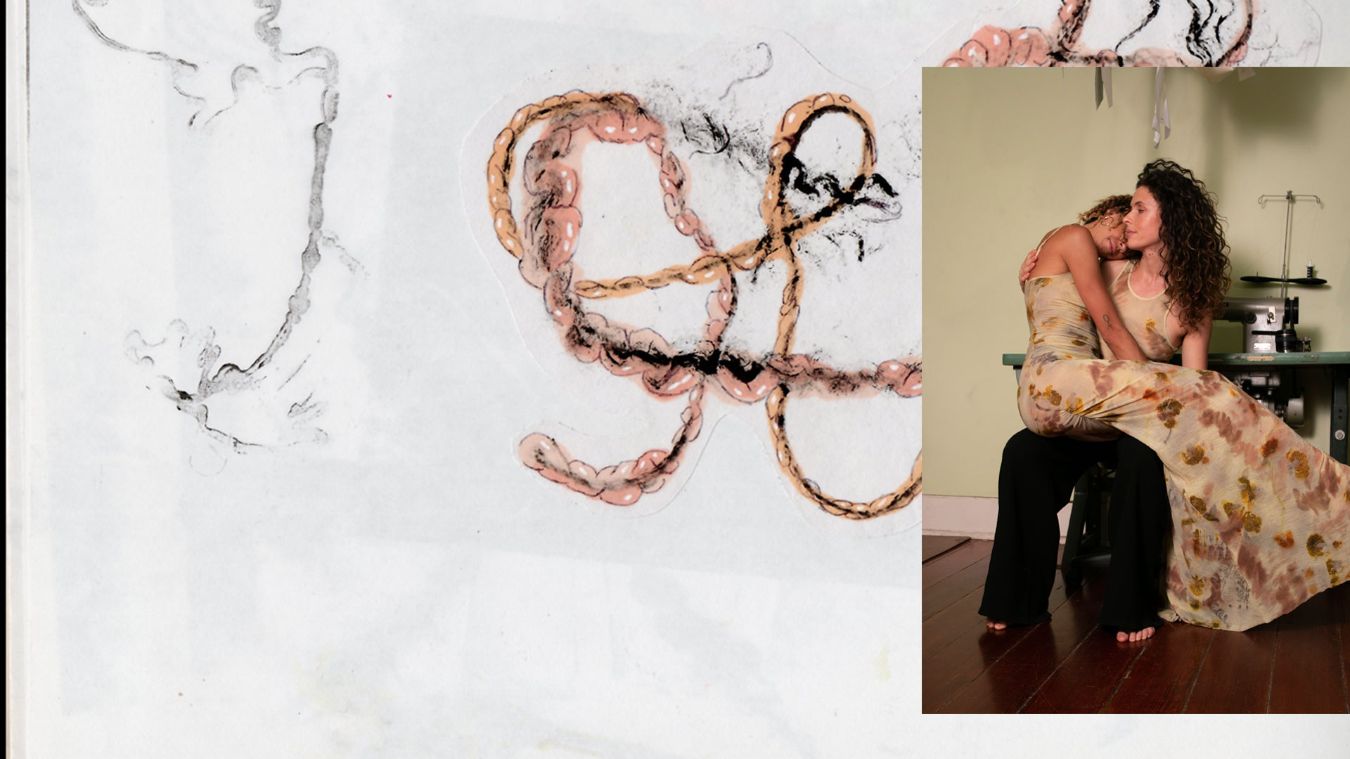 Two women in floral patterned dresses embracing while seated in a room with sewing equipment.