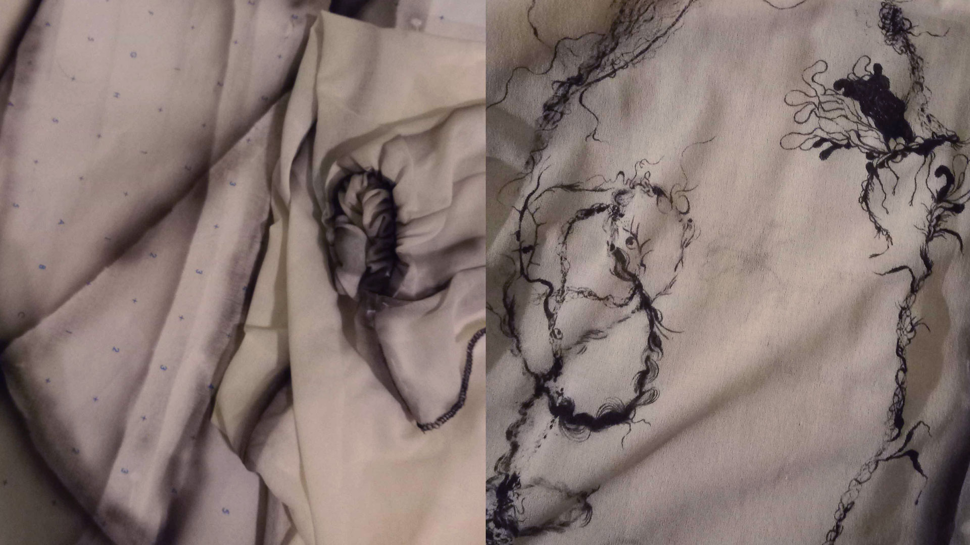 Close-up of beige fabric with black abstract thread embroidery and blue printed numbers and symbols.