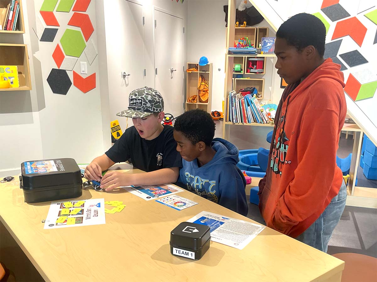 Two middle-school boys try to unlock a box during a challenge.