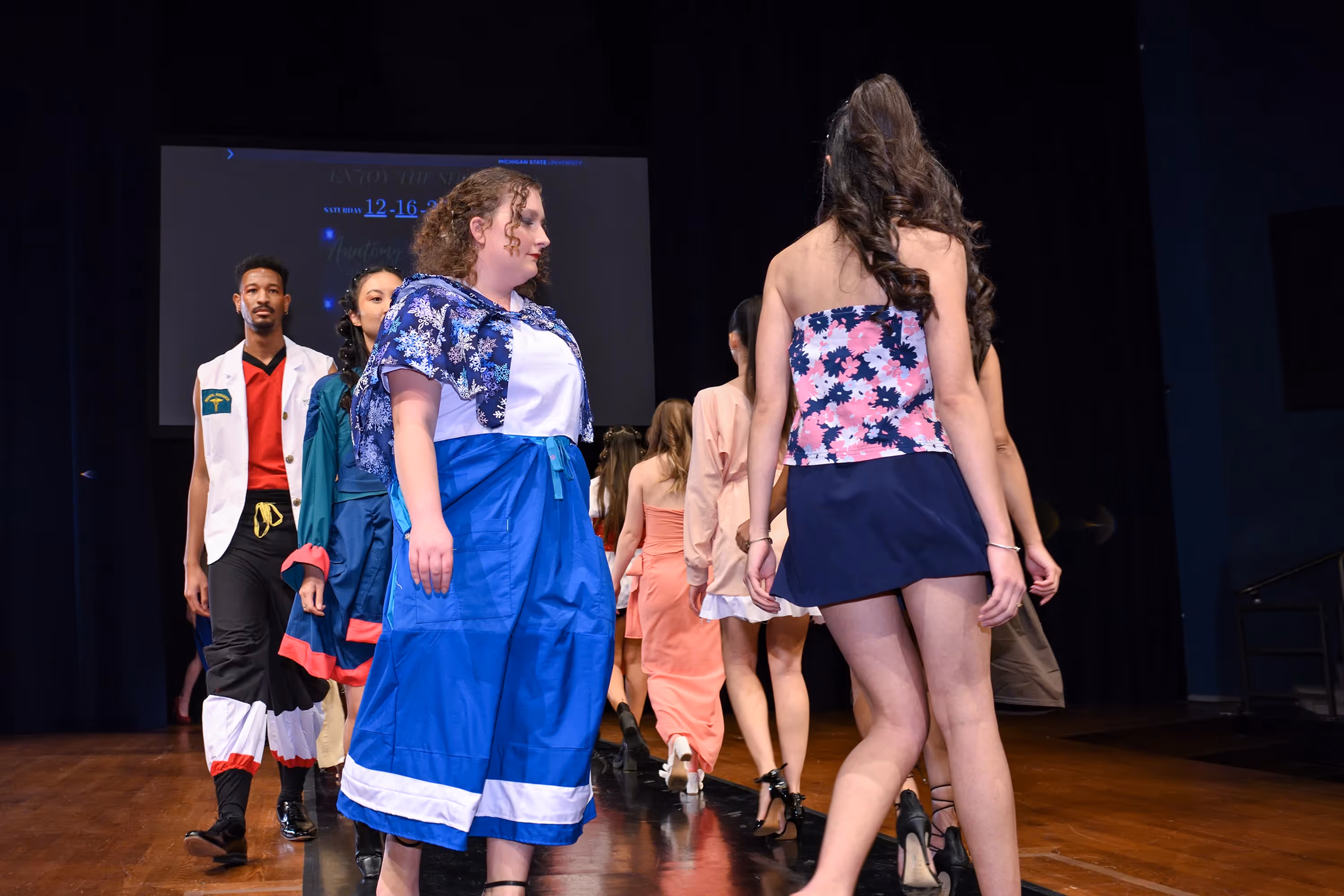 People walking the runway at a fashion show.