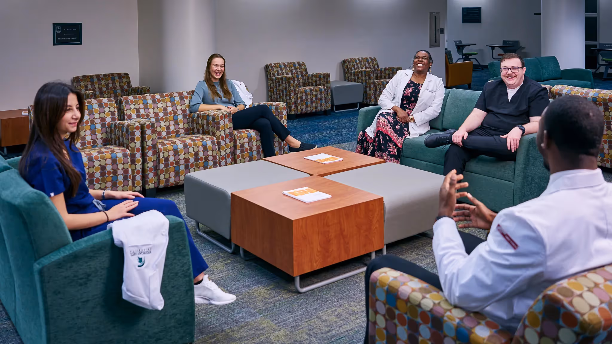 group of students and professionals seated in a lounge area having a discussion in a casual setting