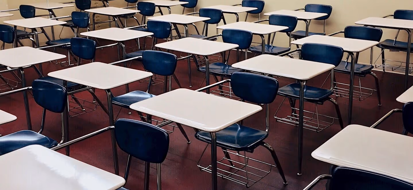 empty classroom filled with rows of individual desks and chairs