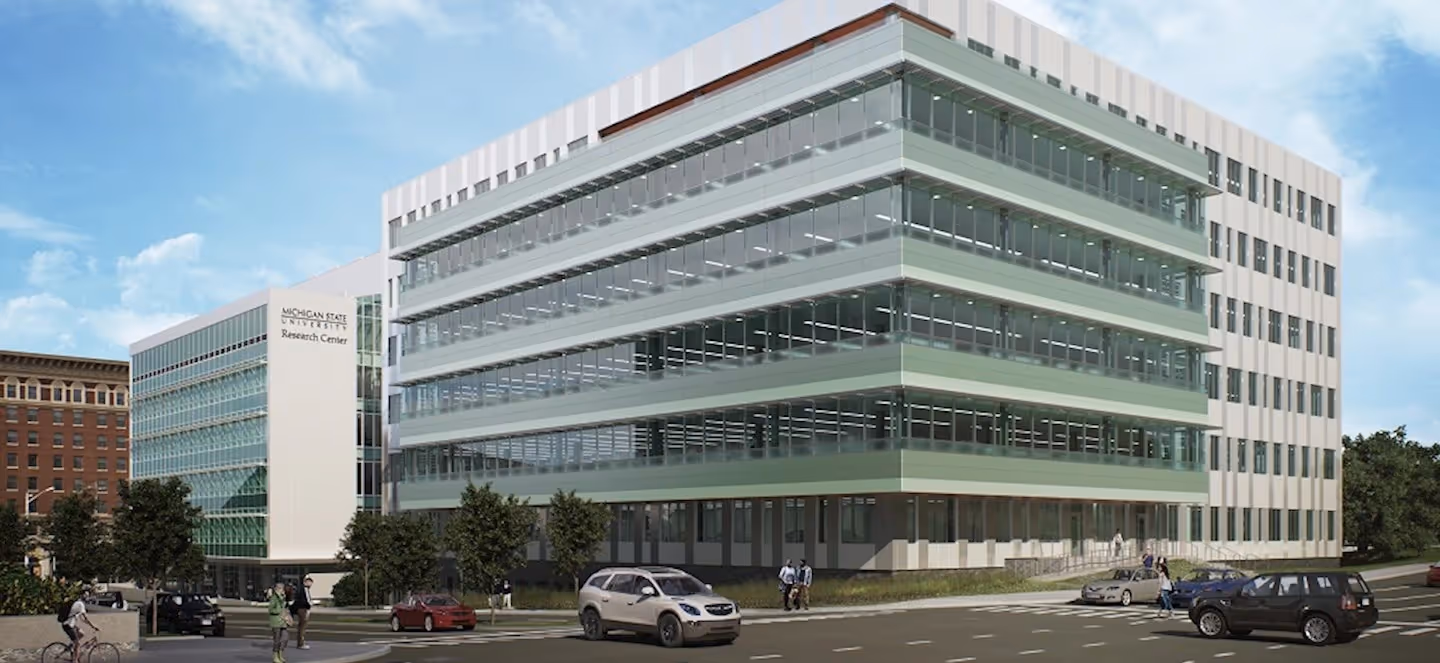 modern multistory research building with glass exterior and street traffic in front