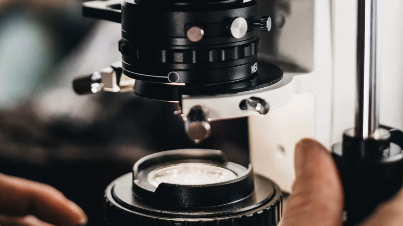 close‑up view of microscope components and specimen tray being adjusted during lab research
