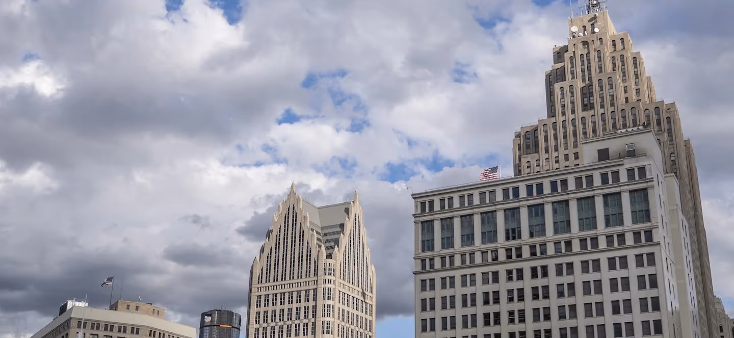 skyline view of downtown Detroit featuring prominent historic skyscrapers under a cloudy sky
