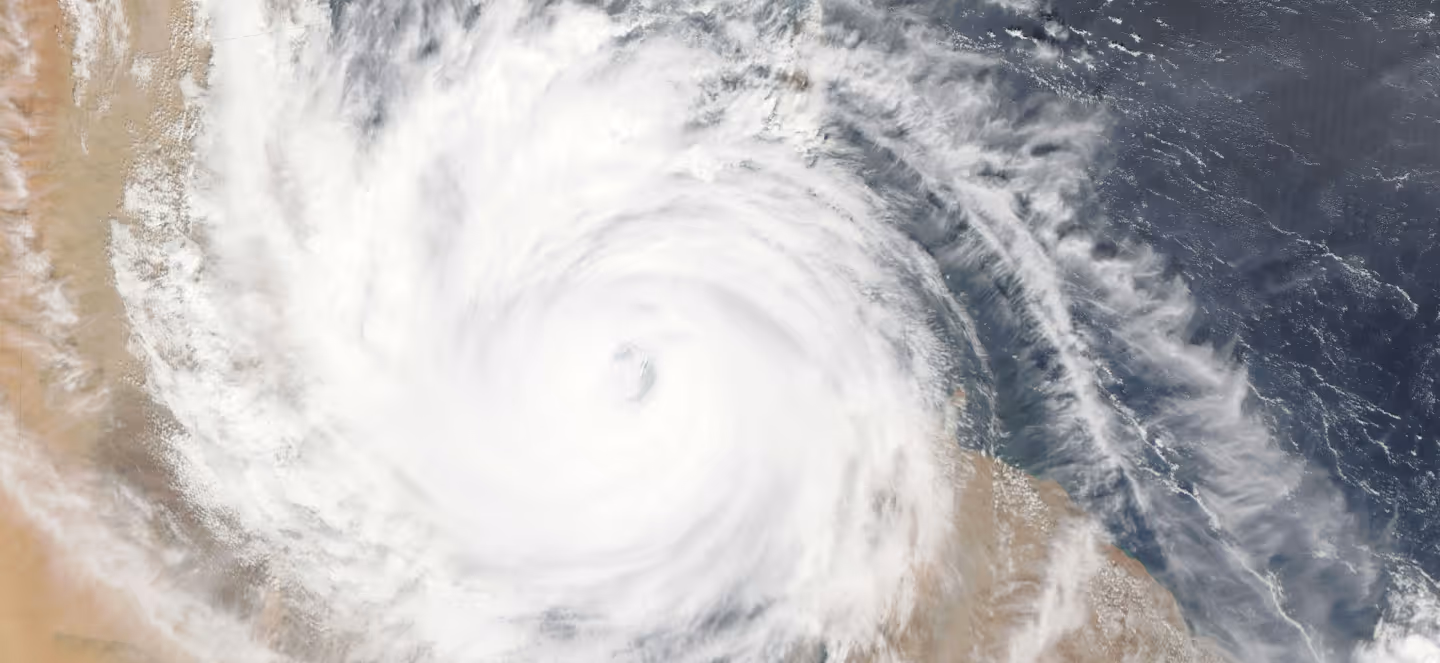 Satellite image of a powerful hurricane with a well-defined eye rotating over the ocean near a coastline.