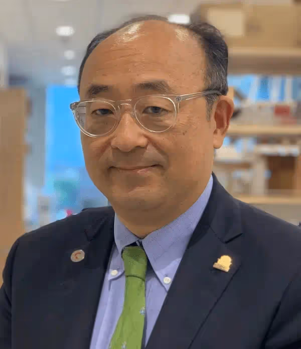 A man in glasses wearing a blue sportcoat over a a purple shirt and a green tie