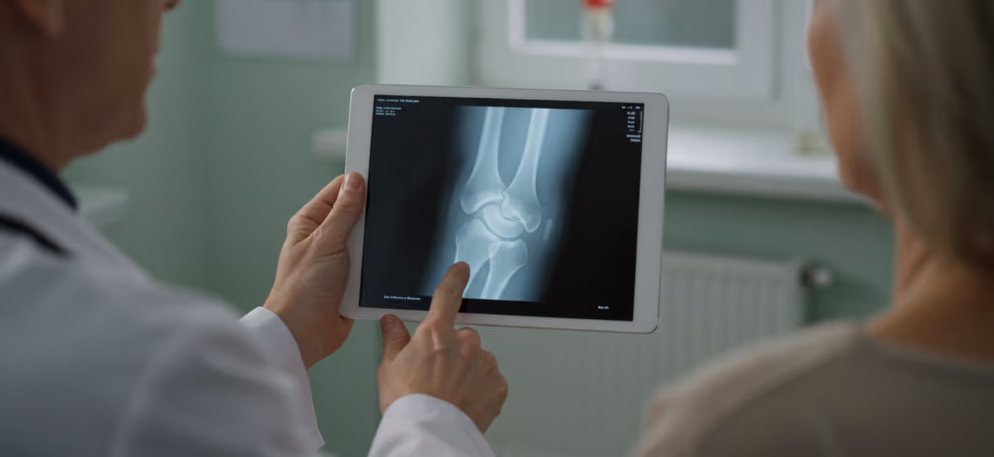 Two people viewing a medical X-ray image on a tablet screen in a clinical setting.