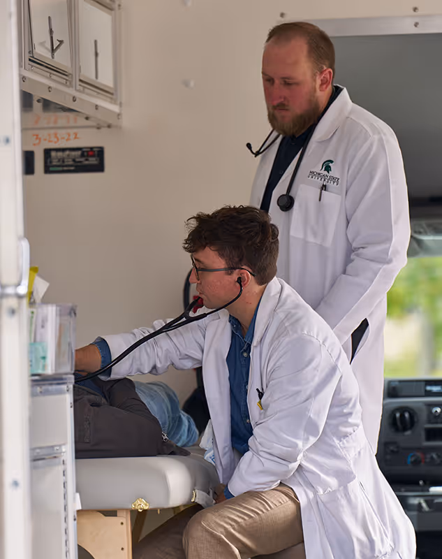 A doctor supervising a student providing care at the Traverse City Mobile Health Clinic.
