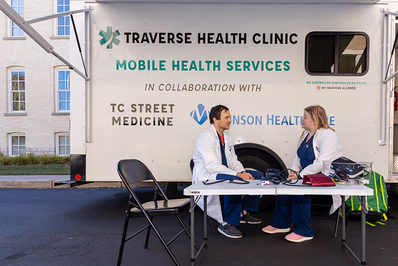 Two doctors talking in front of the Traverse City Mobile Health Clinic.