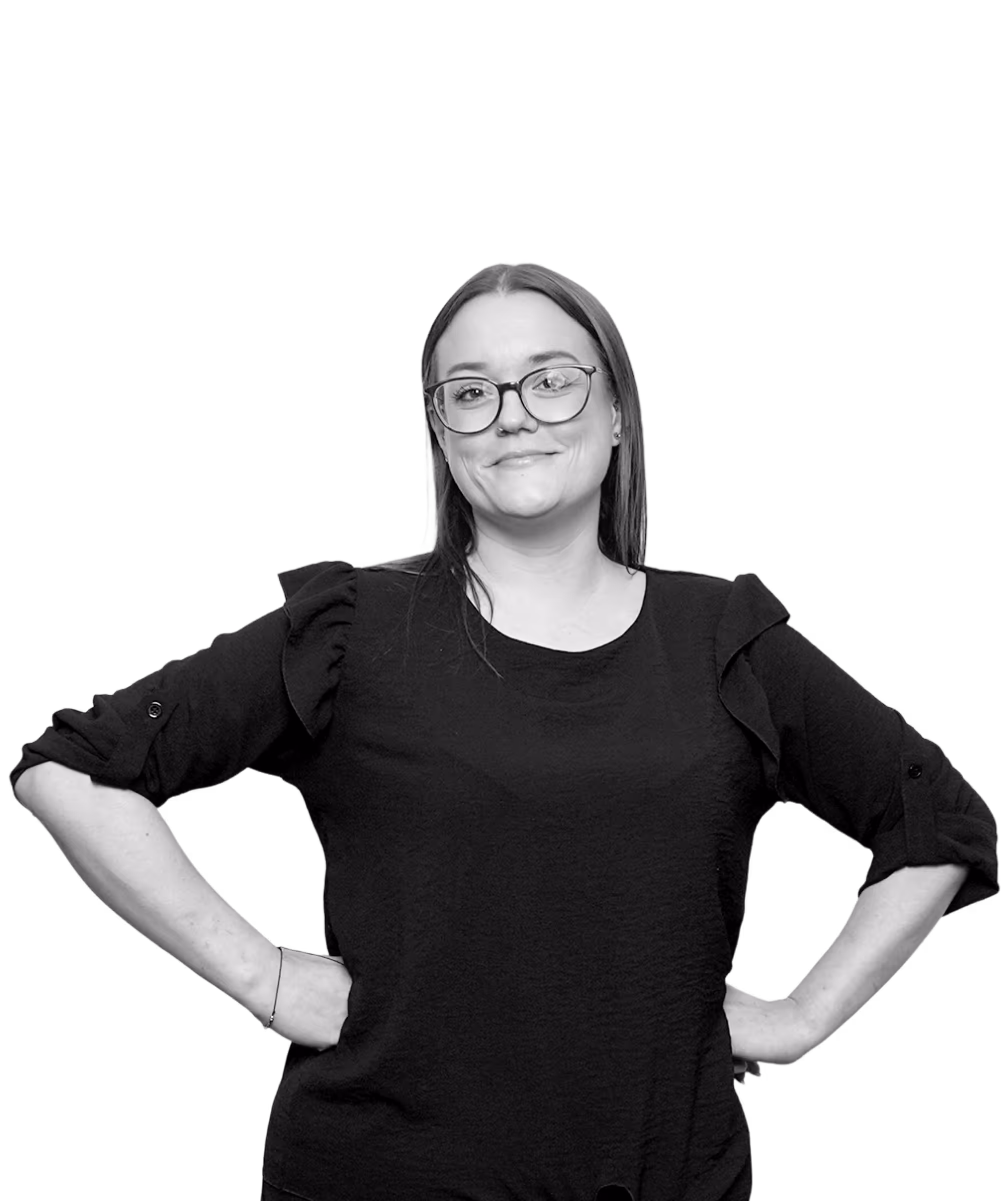 Smiling woman with glasses and long hair wearing a black blouse with ruffled sleeves, standing with hands on hips.