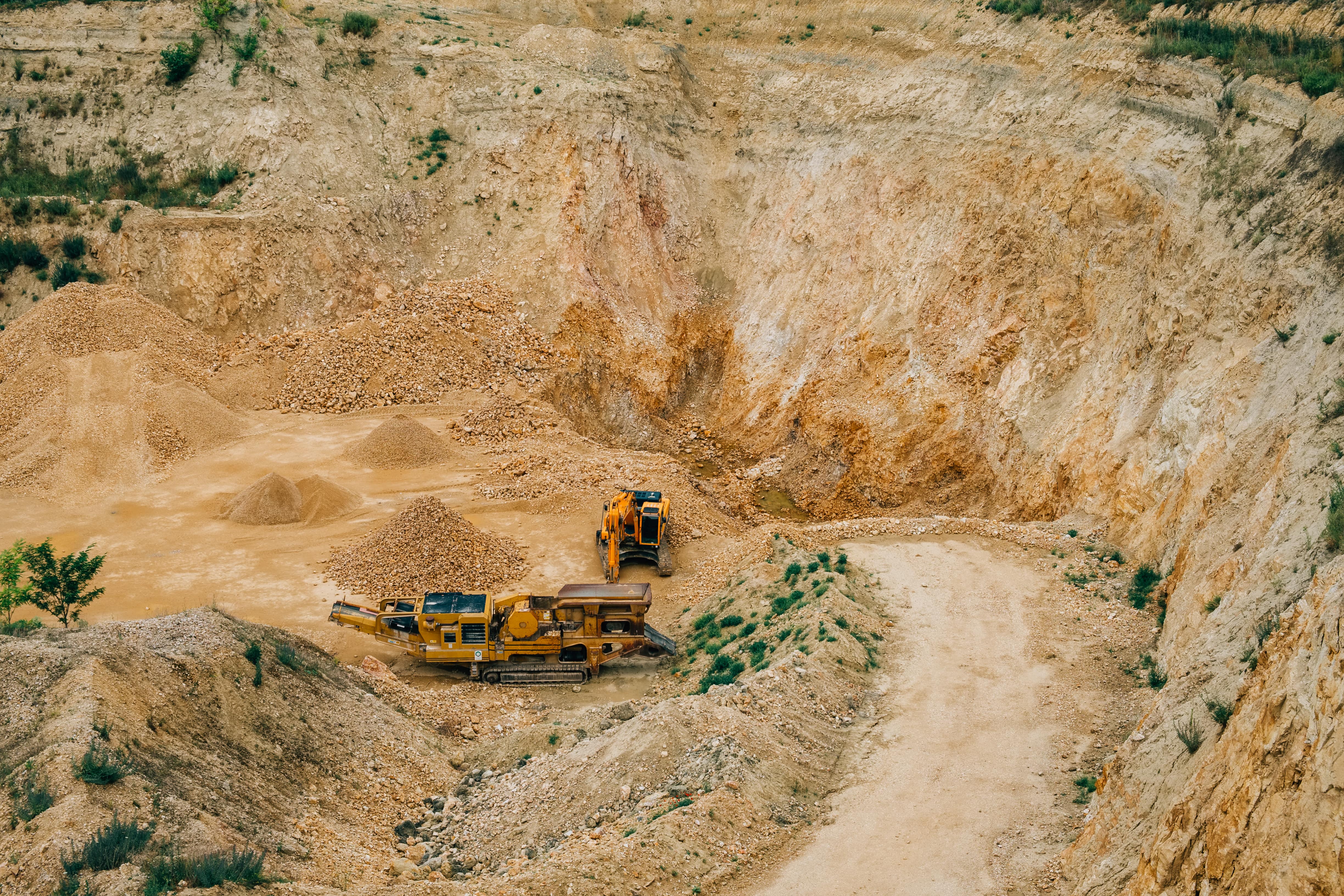 A mining operation with two heavy equipment. Laptop recycling services in Singapore reduce the need for mining.