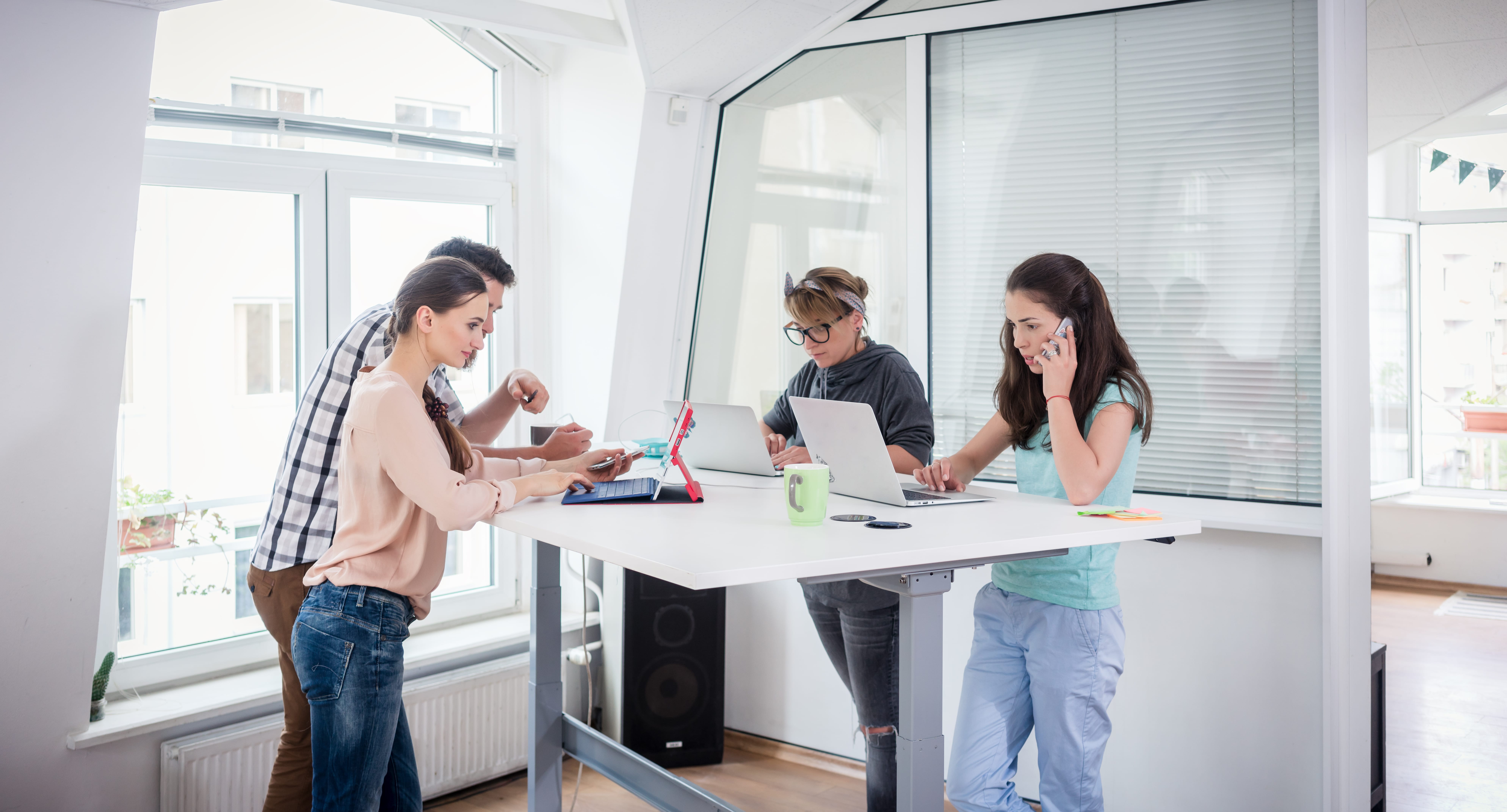 A modern office on a standing desk. Employees are all using laptops. Offices are ideal partners of an e-waste recycling company in Singapore