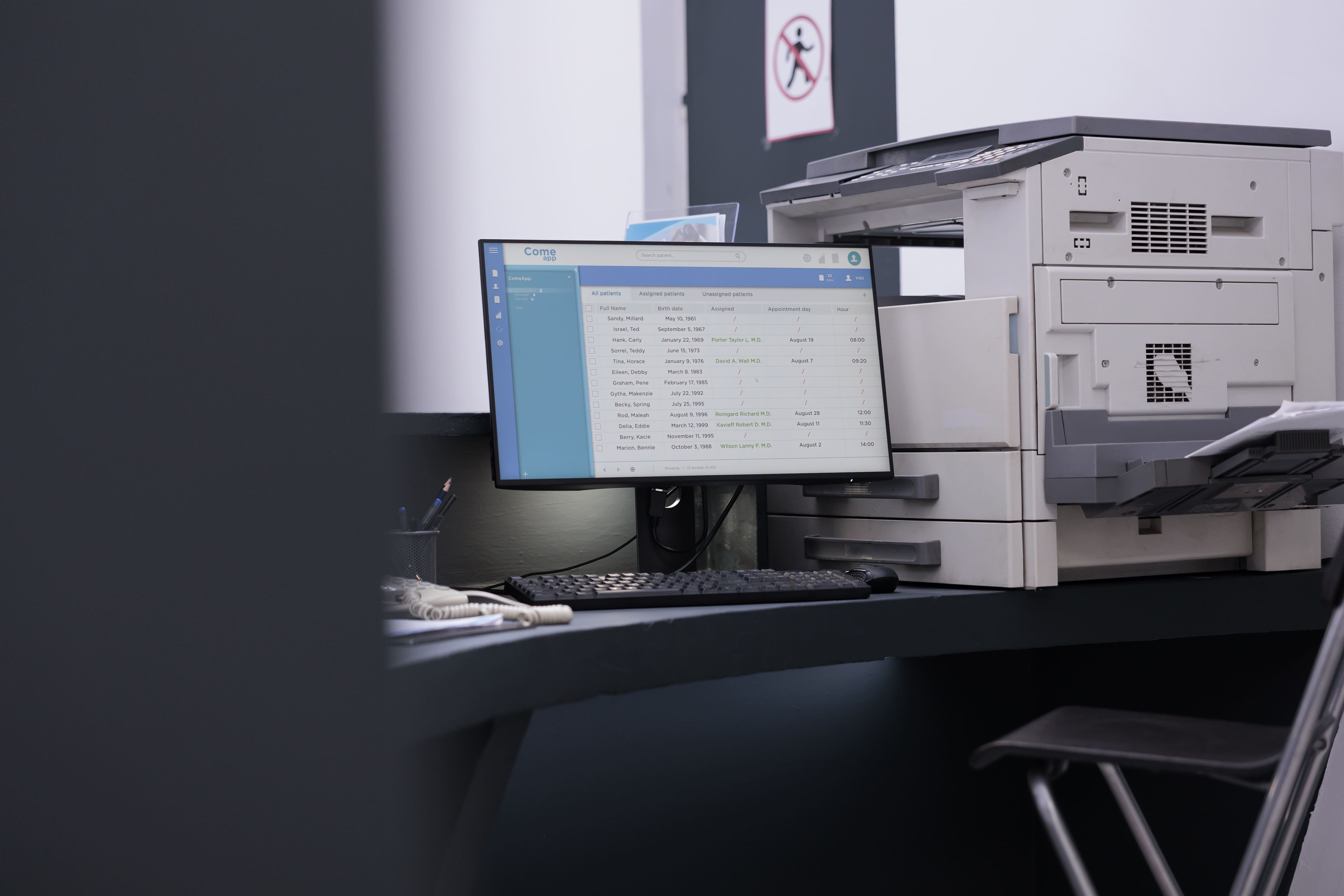 Clinic office desk with computer monitor and medical printer for patient records and administrative work