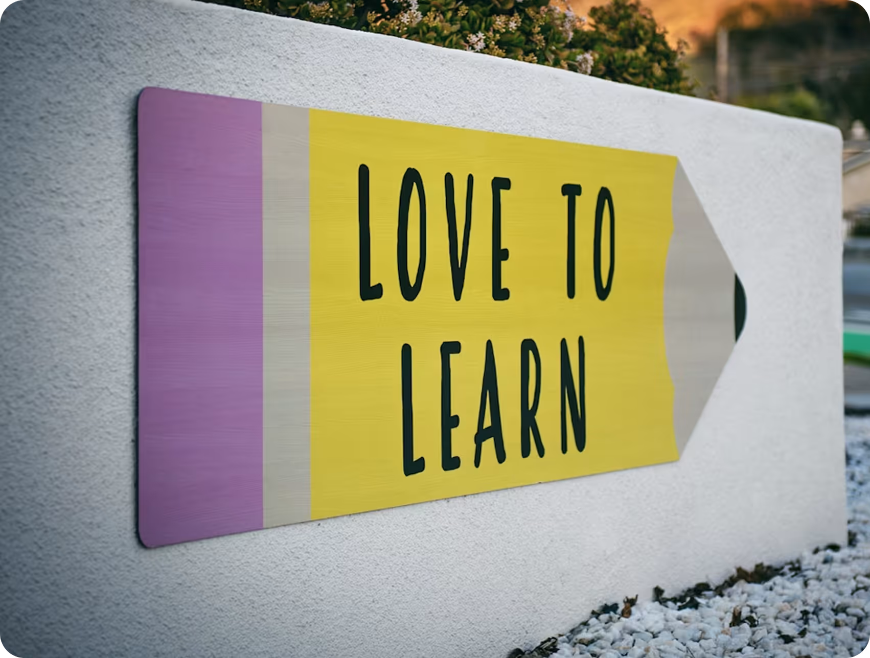Wall-mounted sign shaped like a pencil with purple eraser and yellow body displaying the text 'LOVE TO LEARN'.