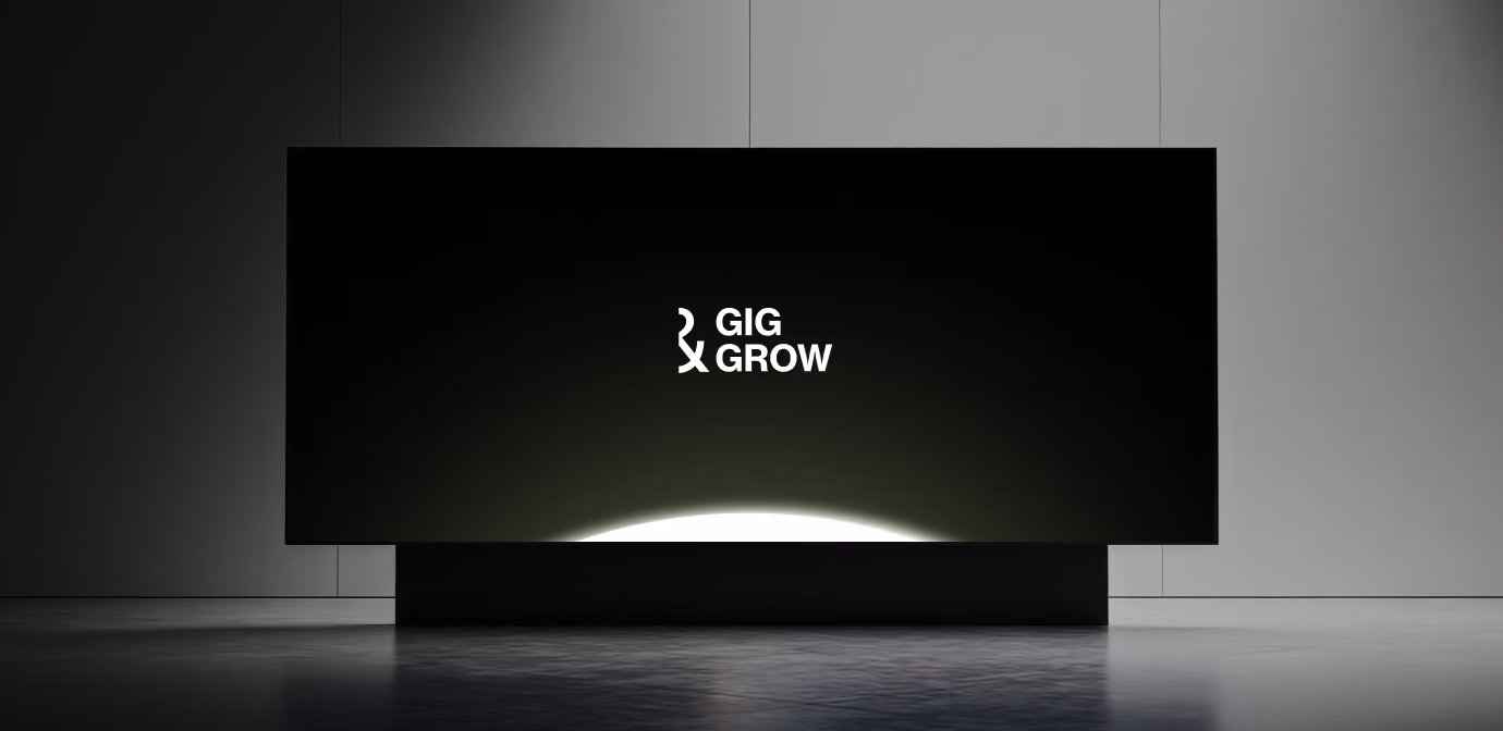 Black rectangular display panel in a minimalist, empty room showing the white text 'GIG GROW' with stylized letters on a dark background illuminated from below.