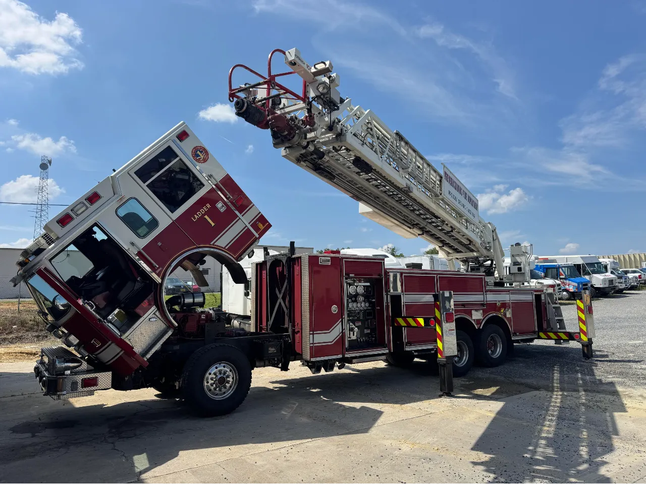 Fire truck ladder inspection with cab tilted forward and aerial ladder extended; text reads “Ladder 1.”
