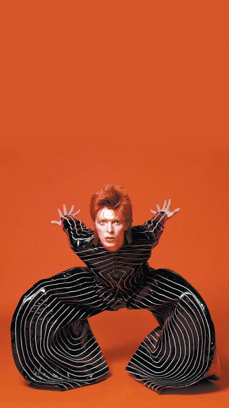 This may contain: a woman in black and white striped pants with her arms stretched out to the side