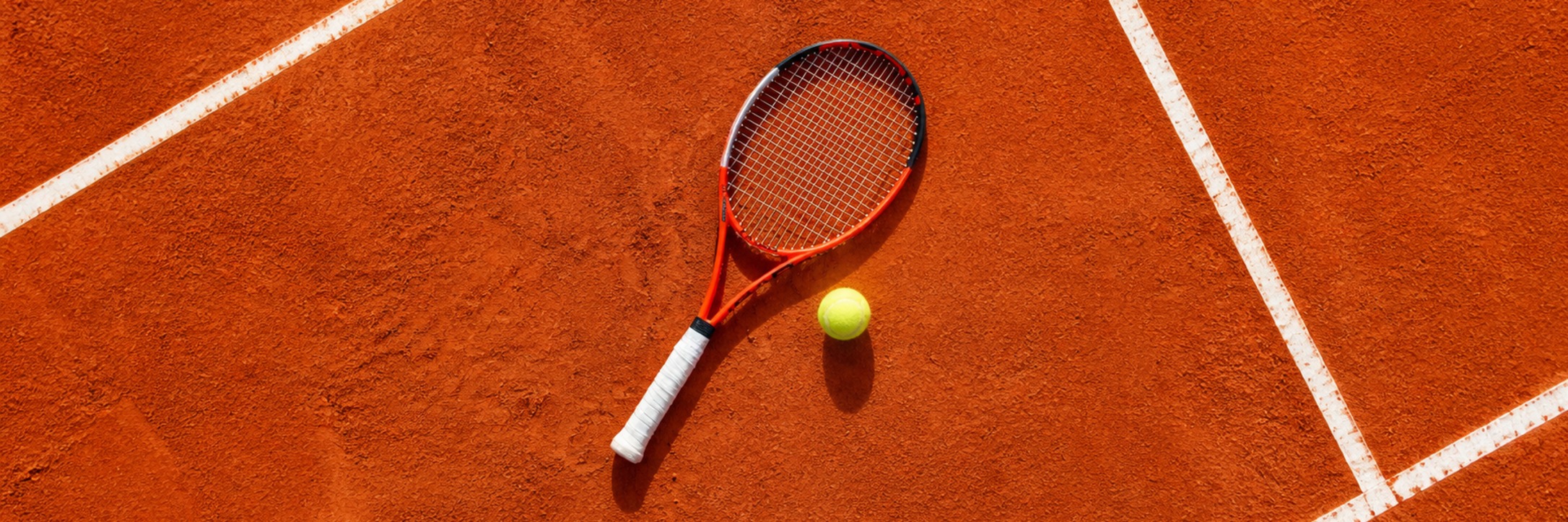Tennisschläger und Tennisball auf einem roten Sandplatz als Motiv für das LK-Turnier beim TV Reutlingen.