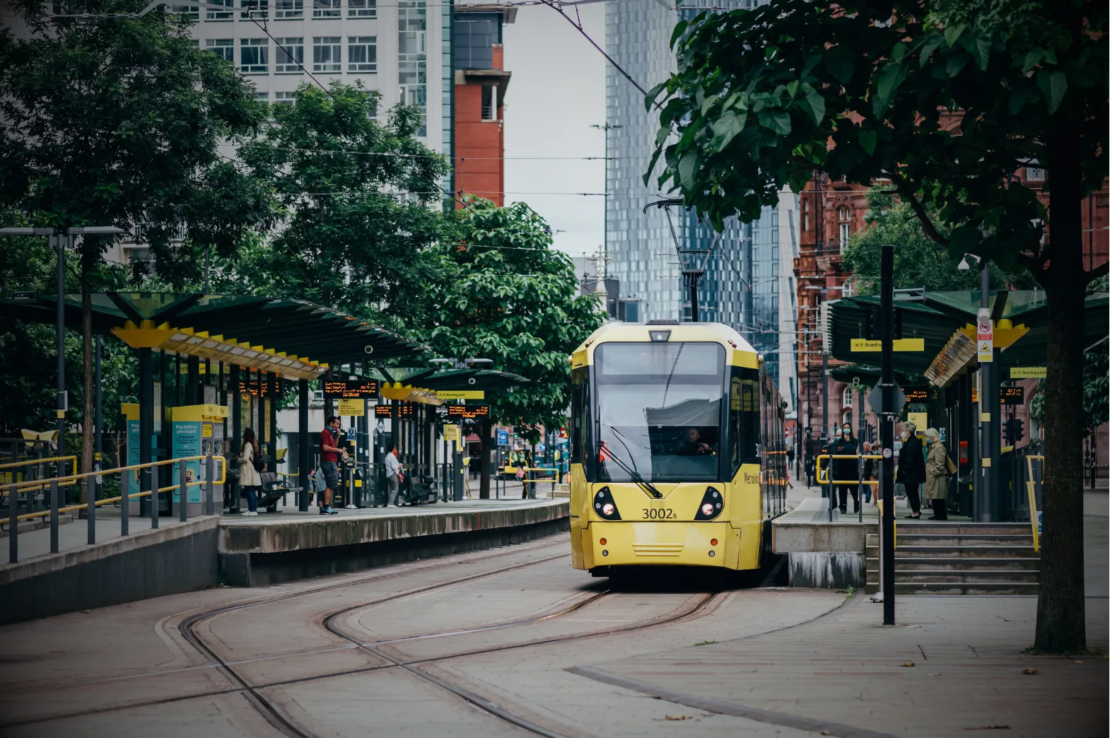 Yellow Metrolink tram at a Manchester city centre stop