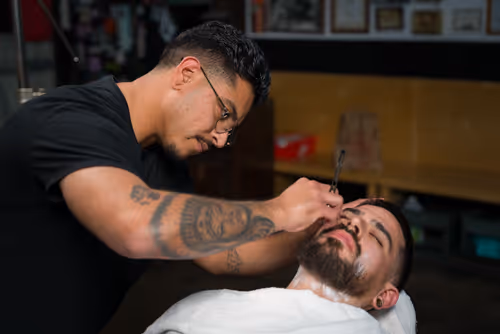 A cinematic image of a barber shaving a man