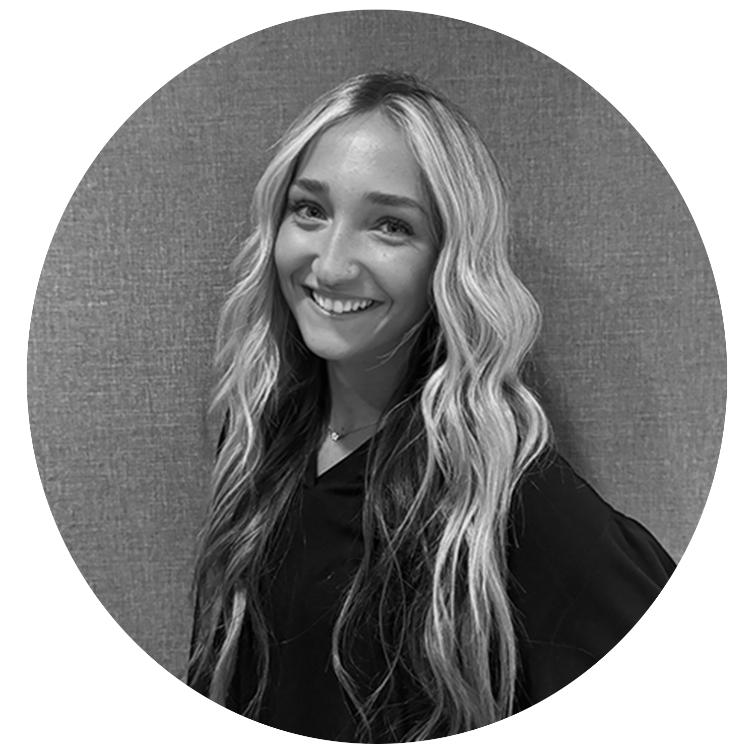 Smiling woman with long wavy blonde hair wearing a dark top against a textured background.