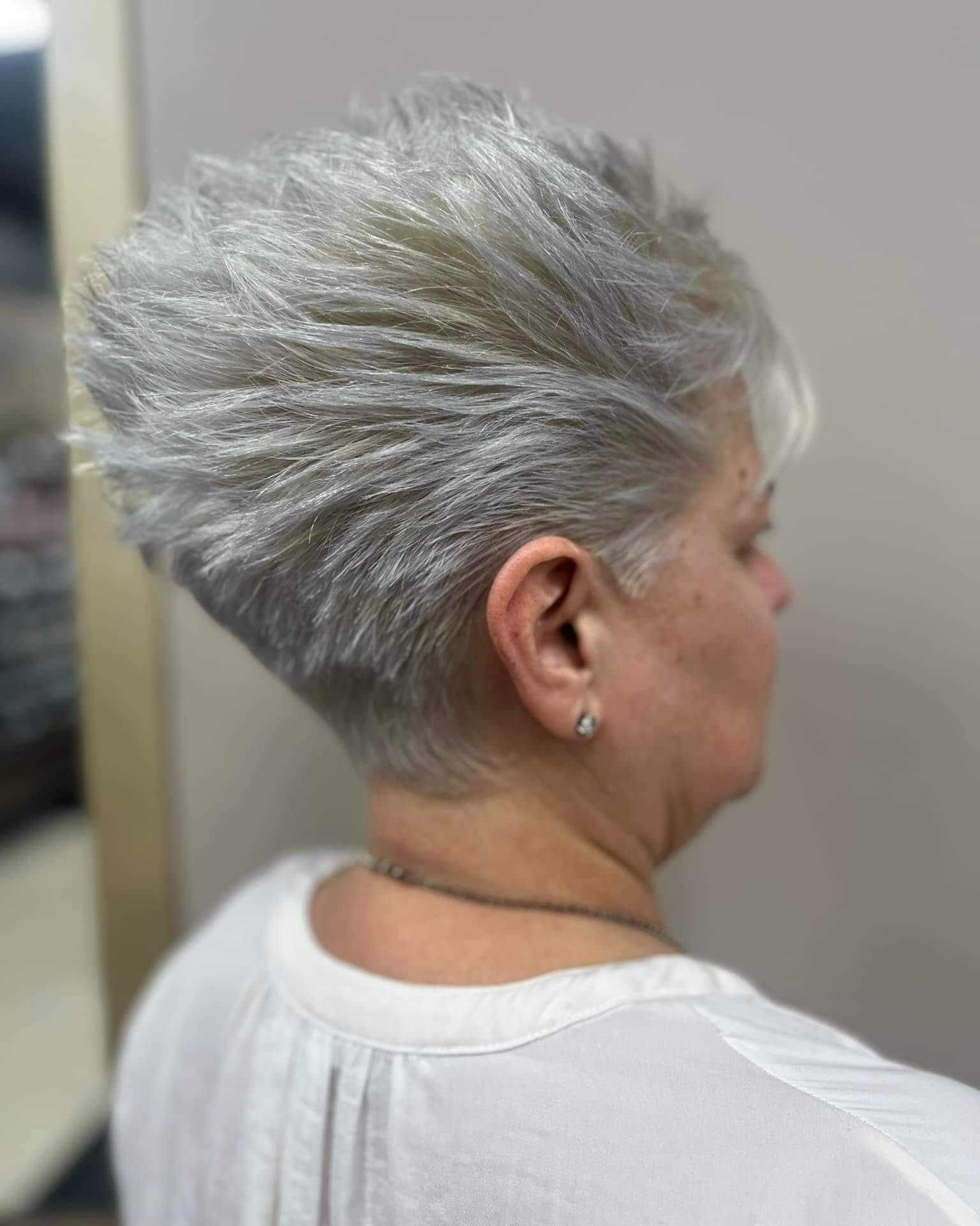 Side and back view of a person with short, textured, silver-gray hair styled upwards.
