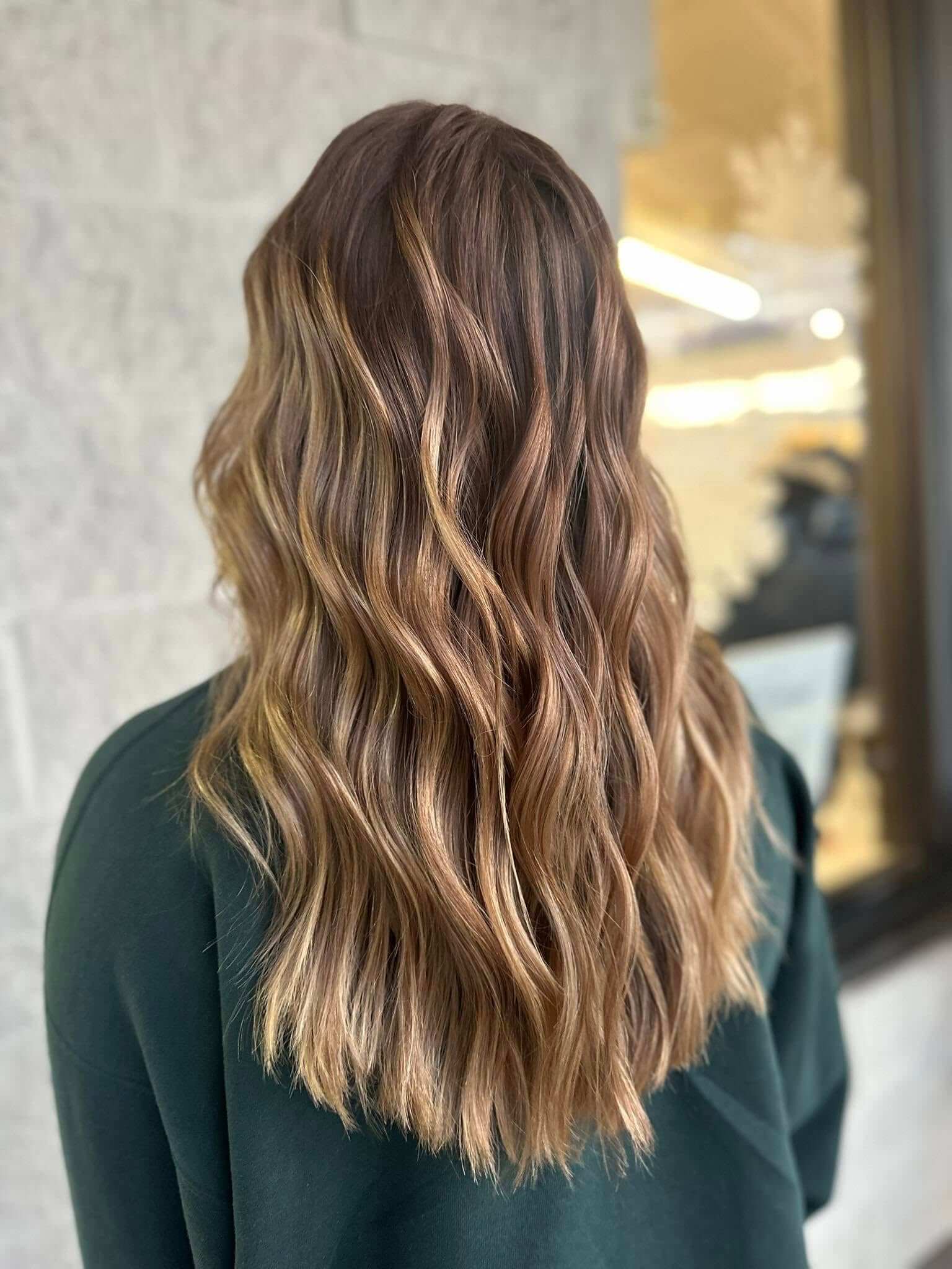 Long wavy hair with soft brown and blonde balayage highlights viewed from the back.