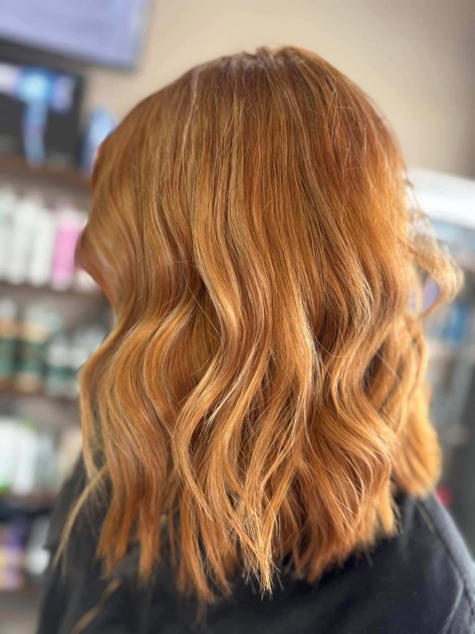 Shoulder-length wavy hair with a warm, reddish-brown color.