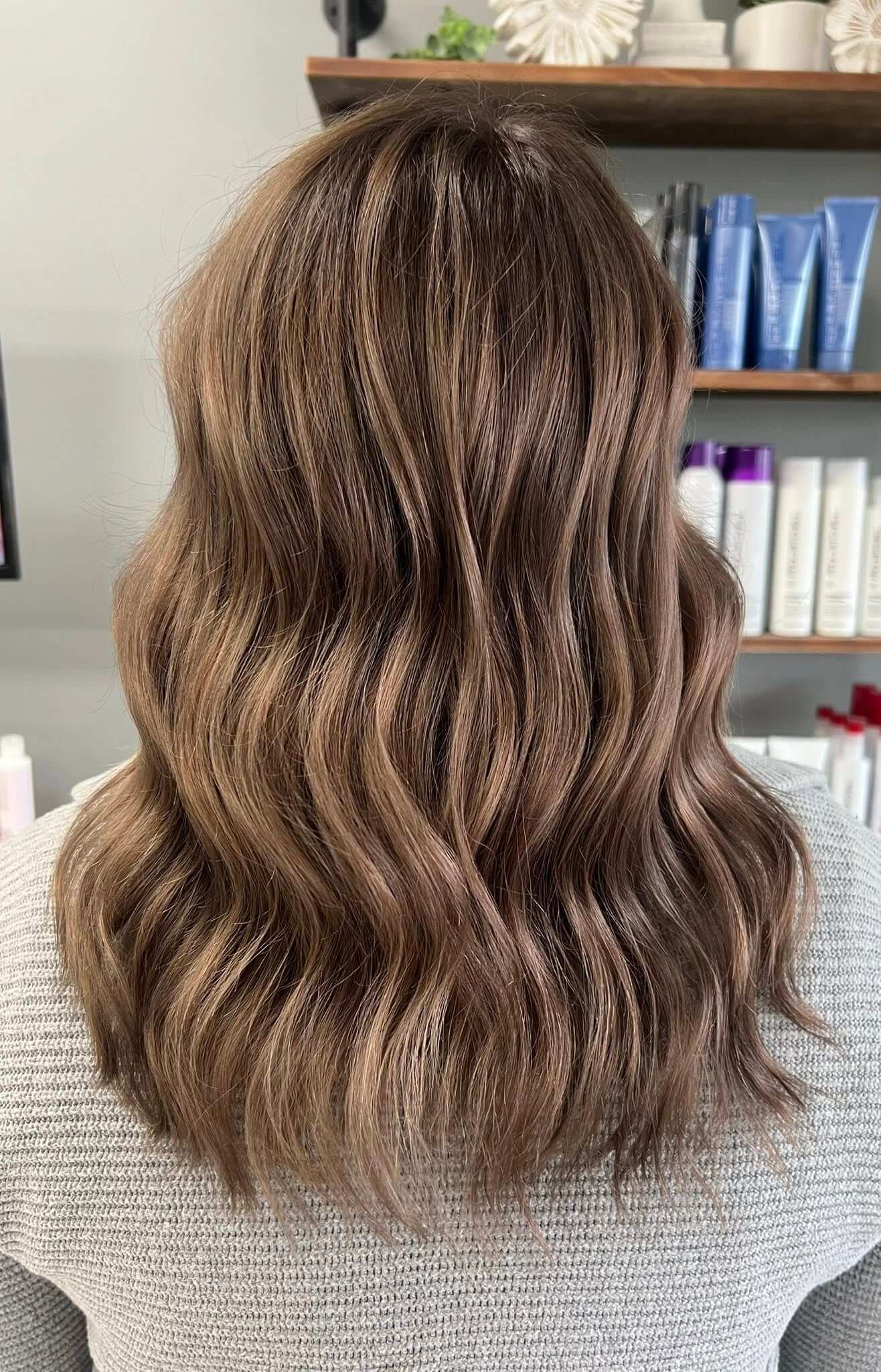 Back view of medium-length wavy hair with a soft brown balayage color.