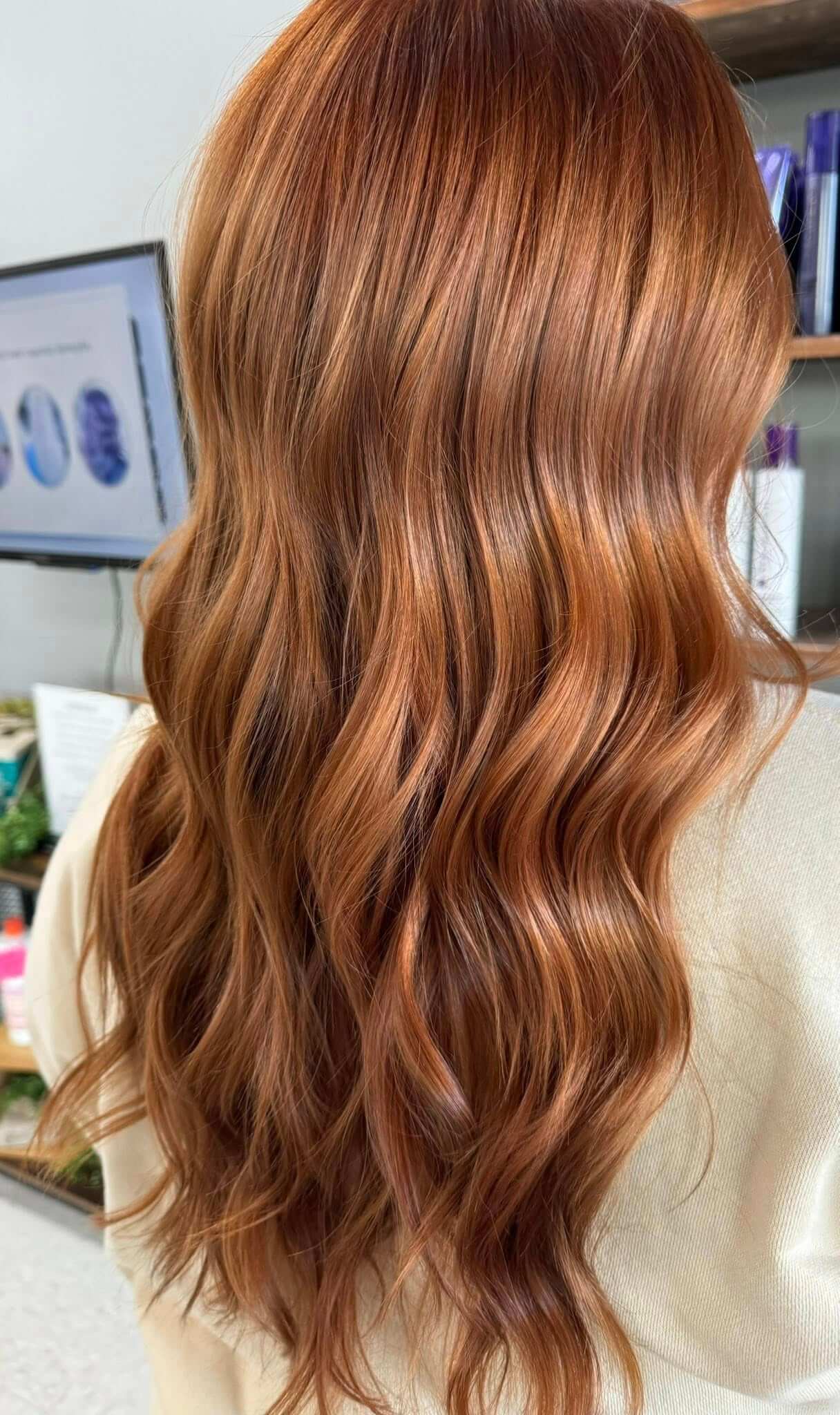 Long, shiny wavy auburn hair viewed from the back.