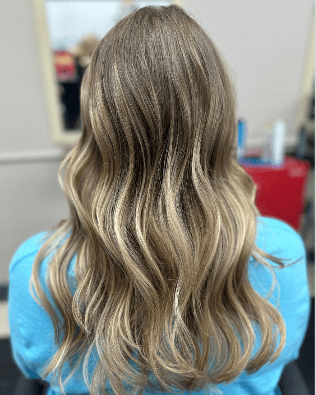 Long wavy hair with a blend of light brown and blonde highlights viewed from the back.