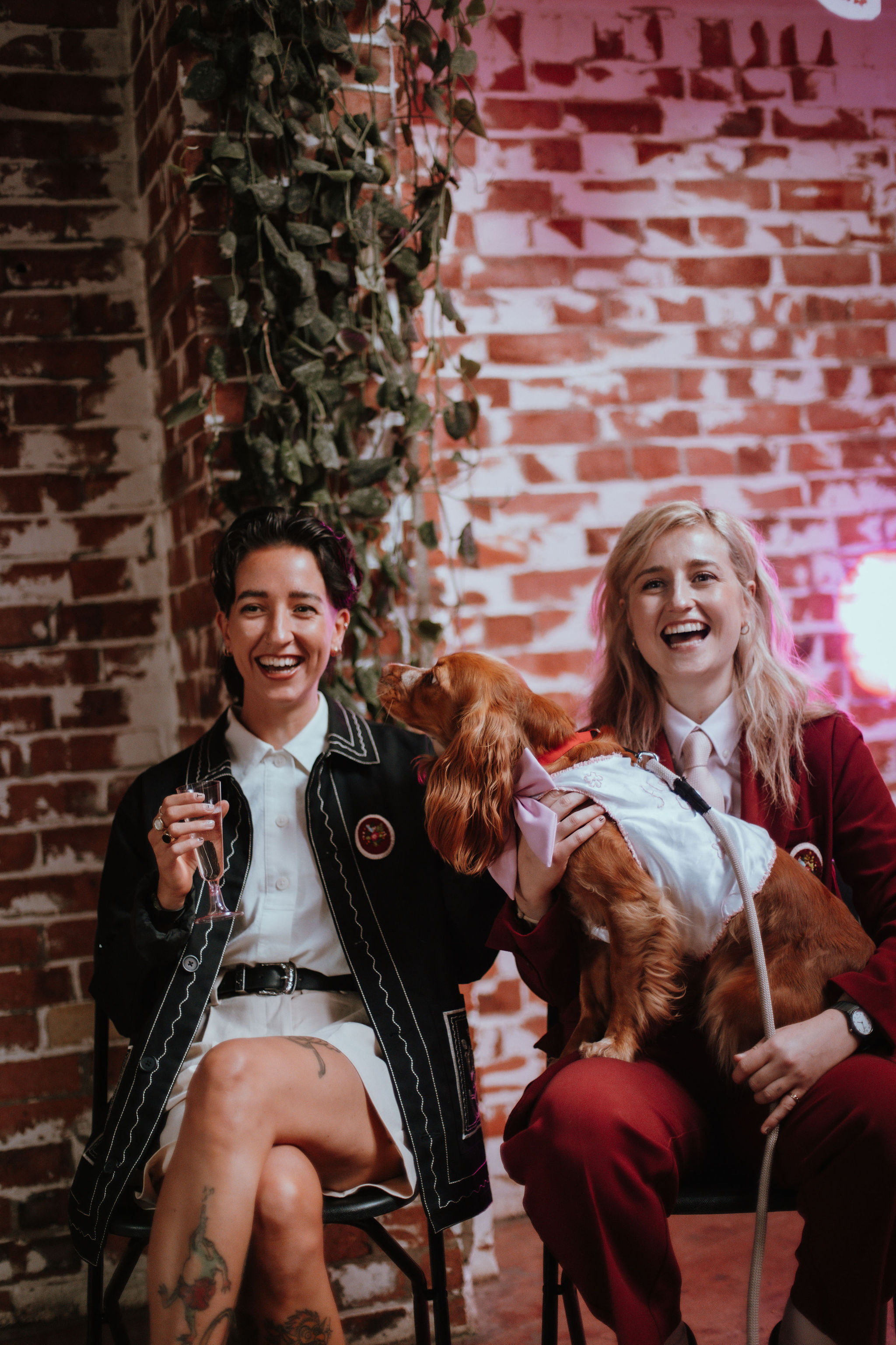 Hayley and Ella laugh on their wedding day, with Lemon the dog. Photo by Kaleido Weddings.