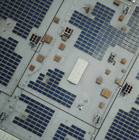 Vogelperspektive: Dach einer Fabrik mit PV-Anlagen darauf.