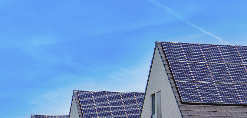 Ein Hausfassade, die von der Sonne bestrahlt wird. Man sieht eine PV Anlage.