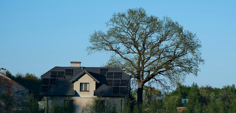 Ein Hausfassade, die von der Sonne bestrahlt wird. Man sieht eine PV Anlage.