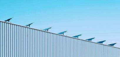 Ein Hausfassade, die von der Sonne bestrahlt wird. Man sieht eine PV Anlage.
