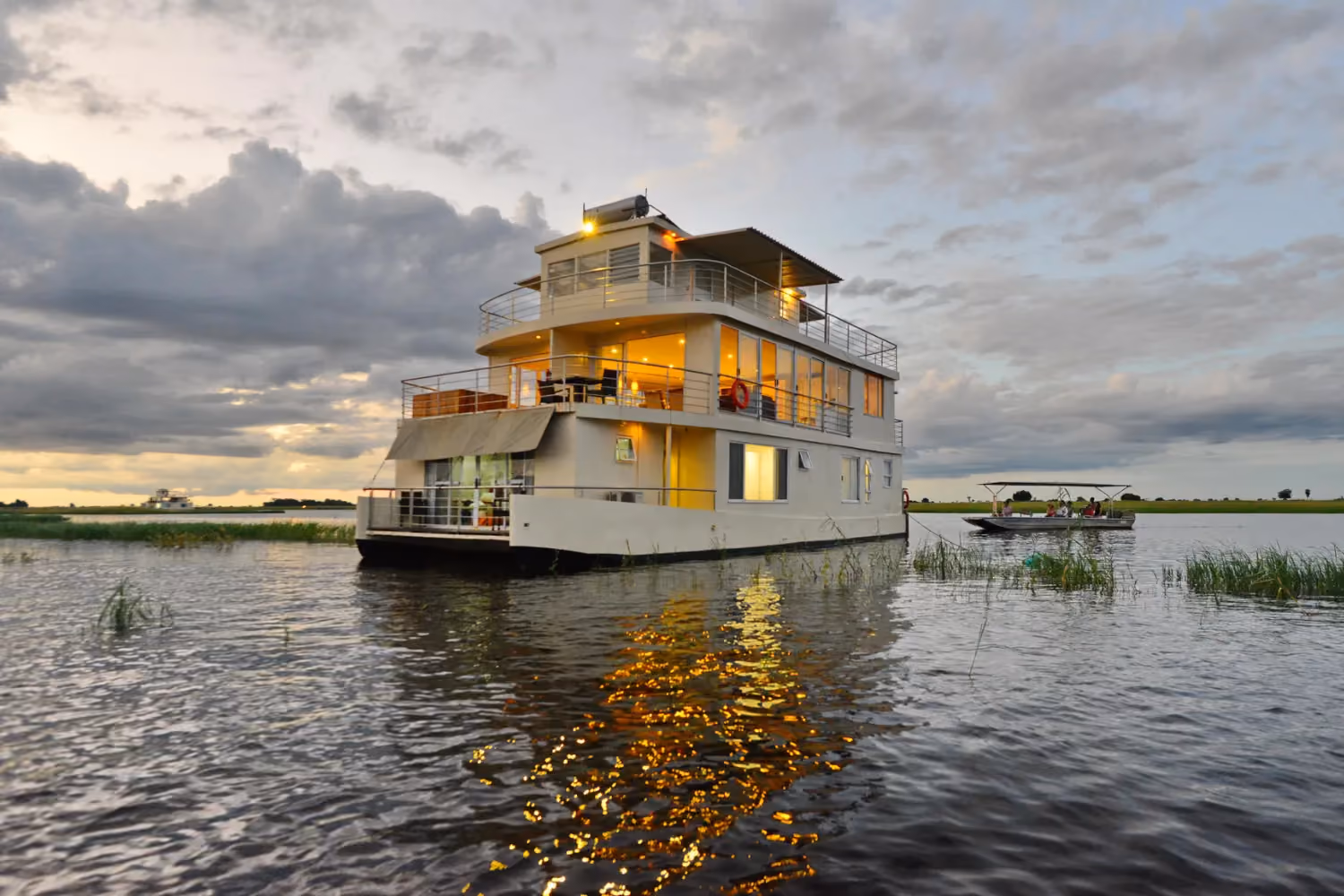 A houseboat floating in the river with lights on