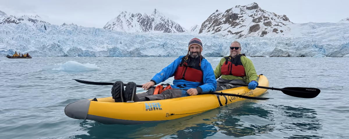 Two men sitting in a kayak on an Arctic expedition.